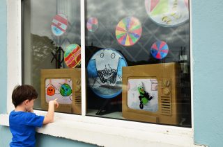 Our World in a Window by Helium Arts: Artist Chelsea Canavan's son is pictured in front of their Limerick home © Chelsea Canavan.